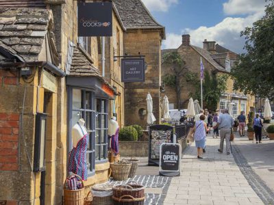 Tourists visiting the picturesque village of Broadway with lovely honey coloured stone houses in The North Cotswolds.