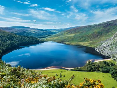 An aerial view of a calm lake surrounded by greenery-covered hills in Wicklow county town of Ireland